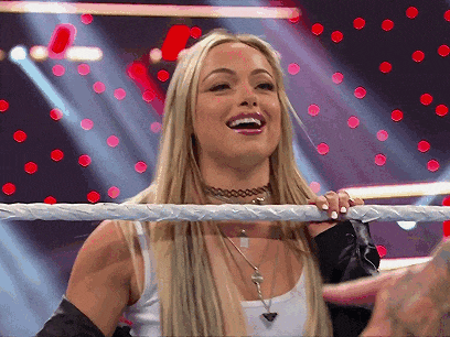 a blonde woman is standing in a wrestling ring smiling .
