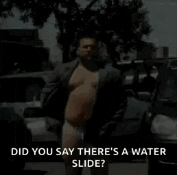 a shirtless man in a suit and underwear is standing in front of a car .
