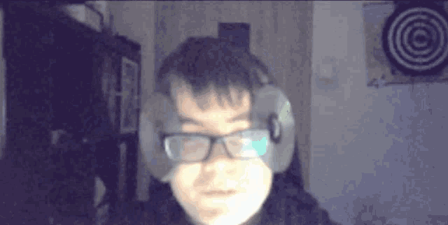 a man wearing glasses and headphones has a cd on his head