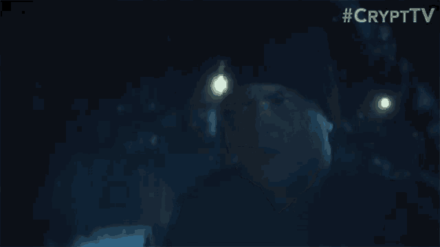 a man in a black hat is standing in the dark .