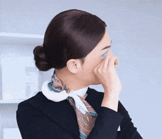 a woman with a scarf around her neck is covering her nose with her hand