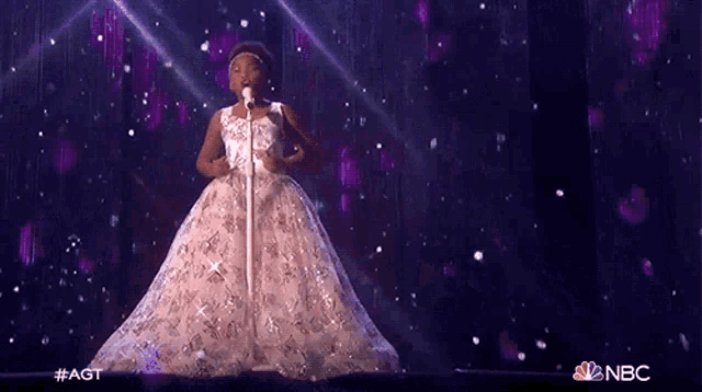 a girl in a white dress singing into a microphone