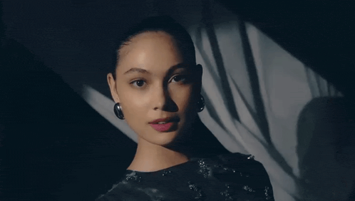 a close up of a woman 's face with a shadow on the wall behind her