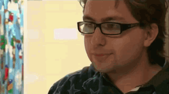 a young man wearing glasses is smiling and looking at the camera