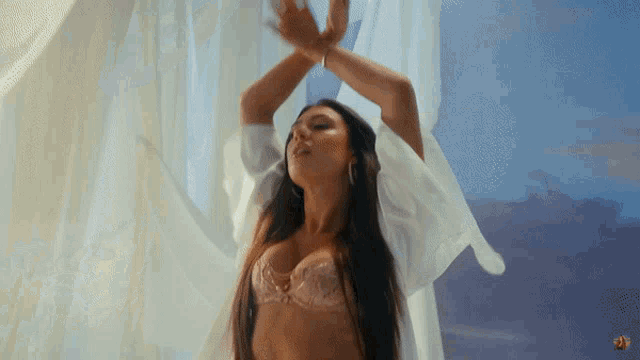 a woman in a bra is standing in front of white curtains
