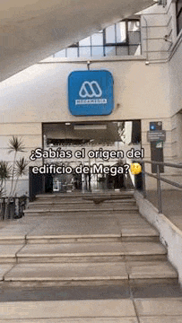 a building with stairs leading up to it and a sign that says `` sabias el origen del edificio de mega ''