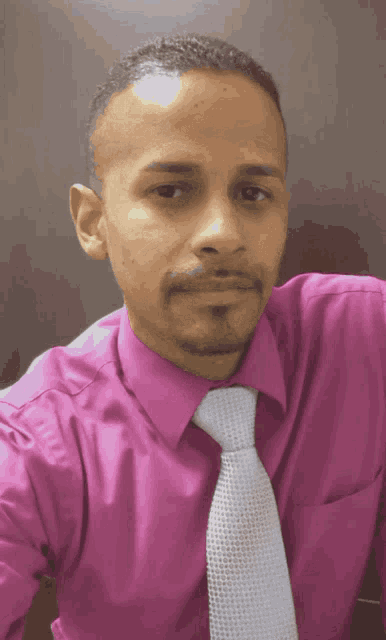 a man is wearing a pink shirt and tie