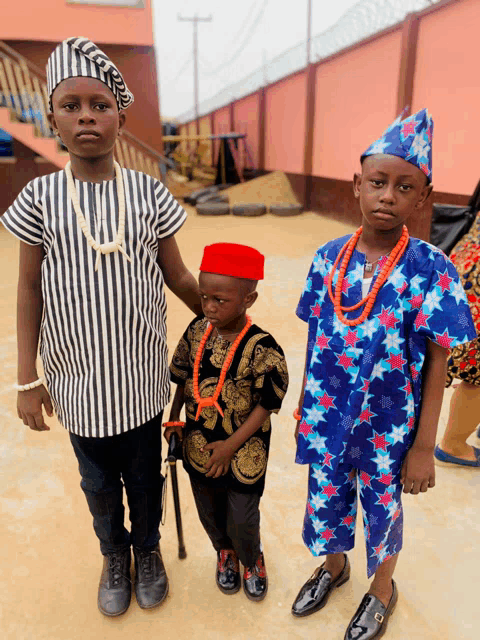 a boy wearing a red hat is standing next to two other children
