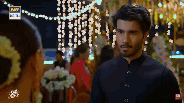 a man and woman are looking at each other in front of a sign that says ' ary digital ' on it