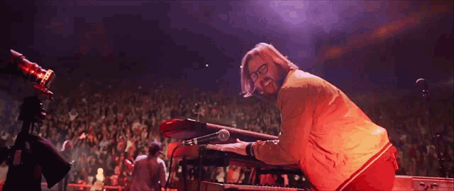 a man playing a keyboard in front of a crowd of people