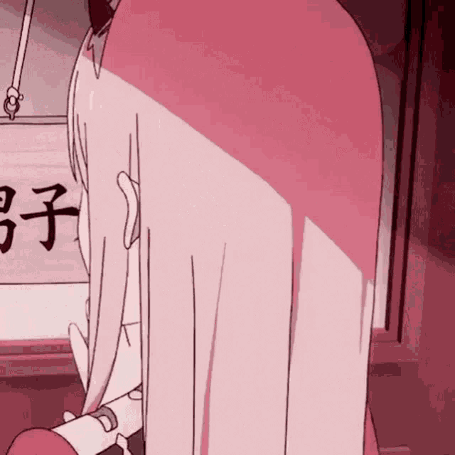 a girl with long pink hair is sitting in front of a sign with chinese characters .