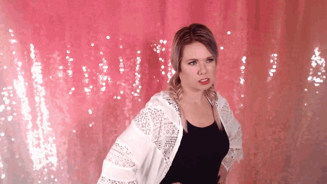 a woman is standing in front of a pink sequined wall