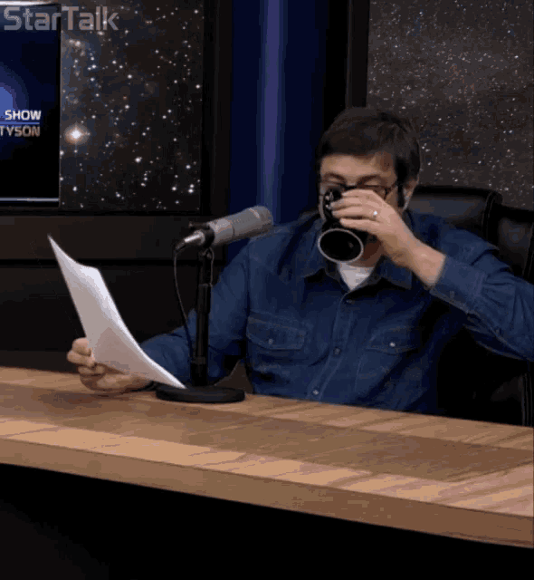 a man sitting at a table with a microphone and a tv screen that says startalk