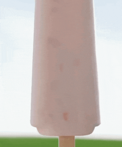 a woman is standing in front of a giant pink ice cream bar .
