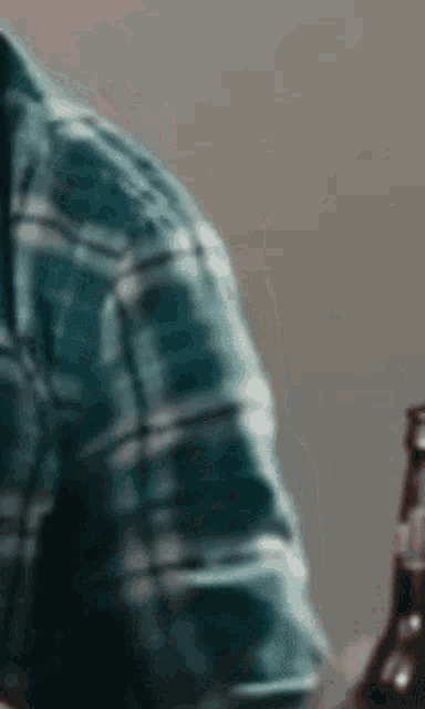 a man in a plaid shirt is sitting at a table with a bottle of beer