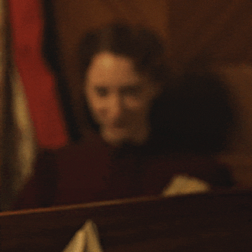 a woman in a maroon shirt is smiling while reading a book