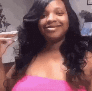 a woman in a pink top is smiling while holding a glass of wine .