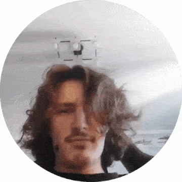 a man with long hair and a beard looks at the camera in a circle