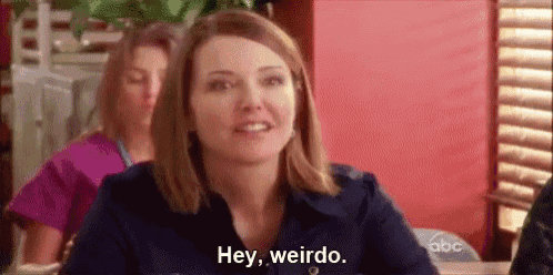 a woman is sitting at a table in a restaurant and saying `` hey , weirdo . ''