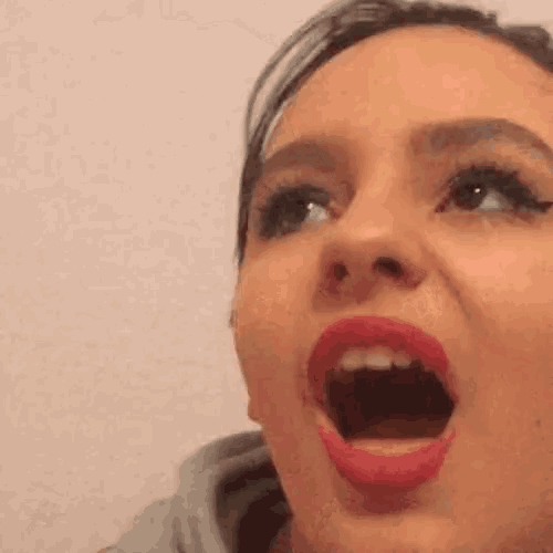 a close up of a woman 's face with her mouth open and red lipstick .