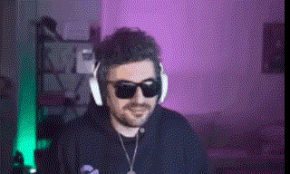 a man wearing sunglasses and headphones is sitting in front of a computer screen .