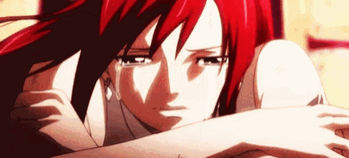 a close up of a girl with red hair crying with her head on her arms .