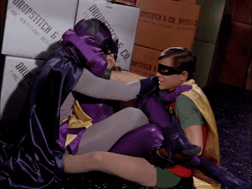 batman and robin are sitting on the floor in front of a box that says drop-stitch 6