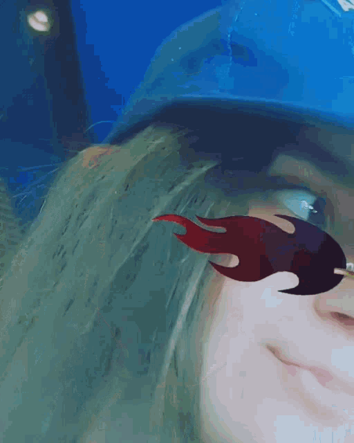 a woman wearing a blue hat and red flames sunglasses smiles