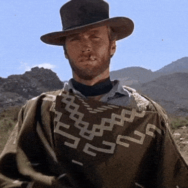 a man with a beard wearing a hat and a poncho with a geometric pattern