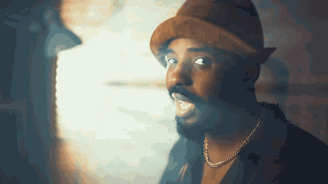 a man with a beard wearing a hat and necklace