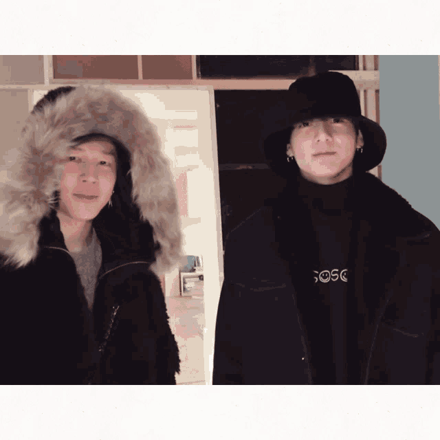 a man wearing a fur hooded jacket and a man wearing a black sweater with the word sosc on the front