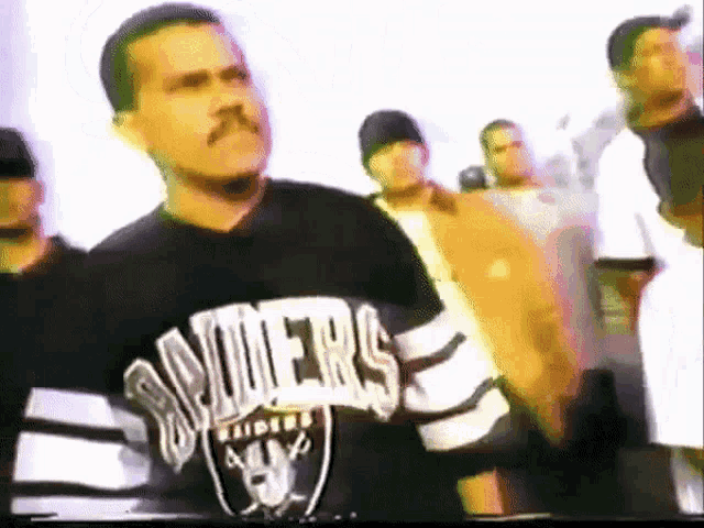 a man in a raiders jersey stands in a crowd