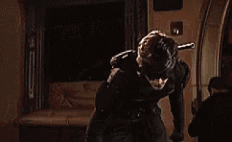 a man in a superhero costume is standing in a dark room looking up .