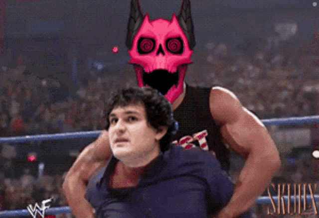 a wrestler with a pink skull on his head is holding a man in a wheelchair