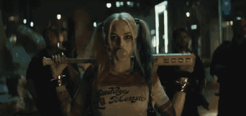 harley quinn from suicide squad is blowing a bubble while holding a bat on her shoulder .