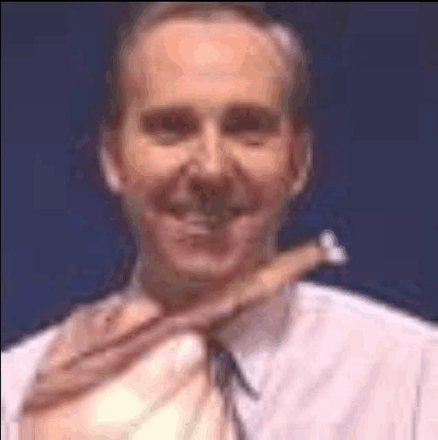 a man in a white shirt and tie is smiling and holding a piece of meat .