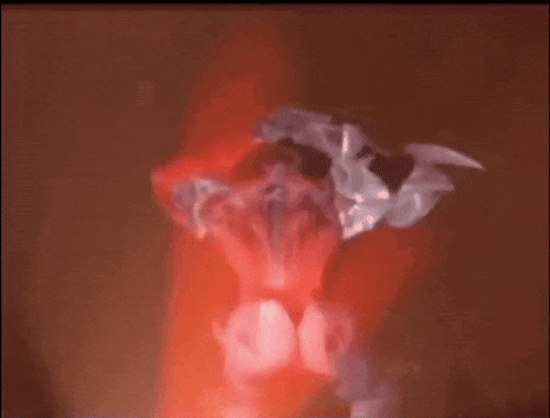 a blurred image of a person standing in a dark room with a red light behind them .