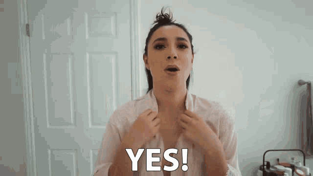 a woman says yes with her arms outstretched in front of a door