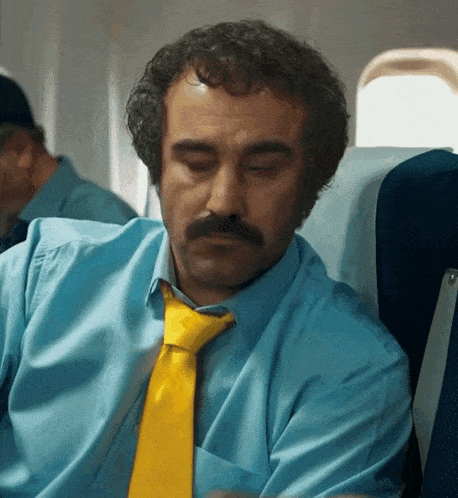 a man wearing a blue shirt and a yellow tie is sleeping
