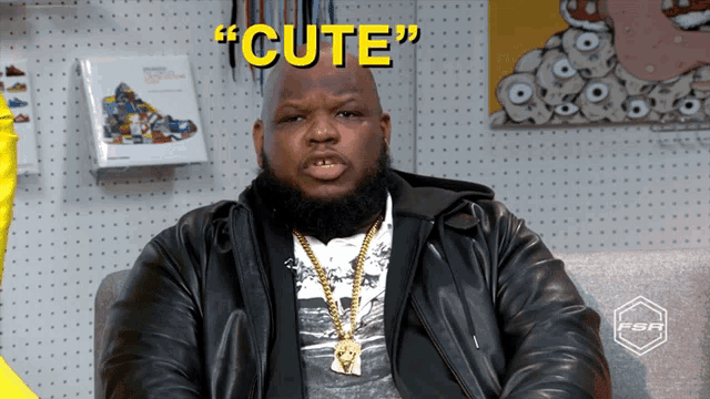 a man in a leather jacket is sitting in front of a wall that says " cute "