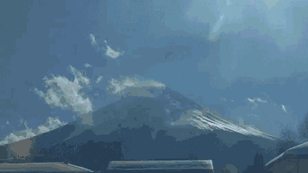 a mountain with a blue sky and clouds in the background
