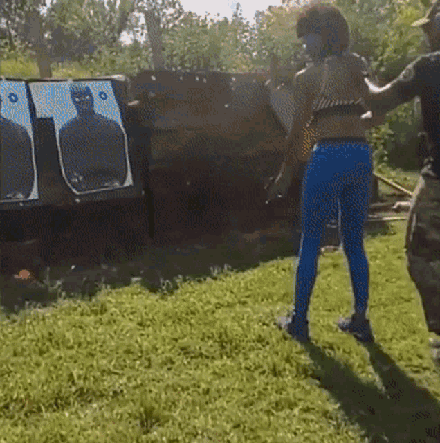 a woman in blue pants is standing in front of a target that has a man on it