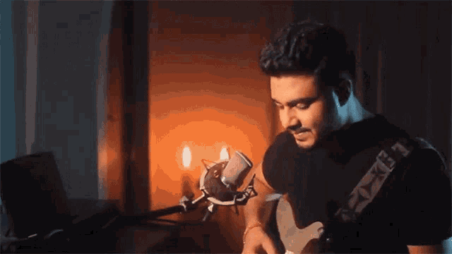 a man is playing a guitar in front of a microphone with a strap that says ' x ' on it