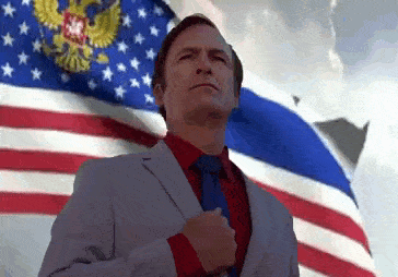 a man in a suit and tie stands in front of an american flag
