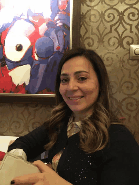 a woman is smiling in front of a painting