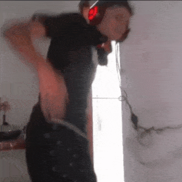 a man wearing headphones and a helmet is standing in front of a refrigerator .