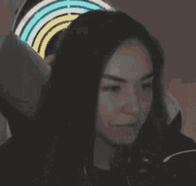 a woman is sitting in front of a microphone while wearing headphones and a rainbow in her hair .