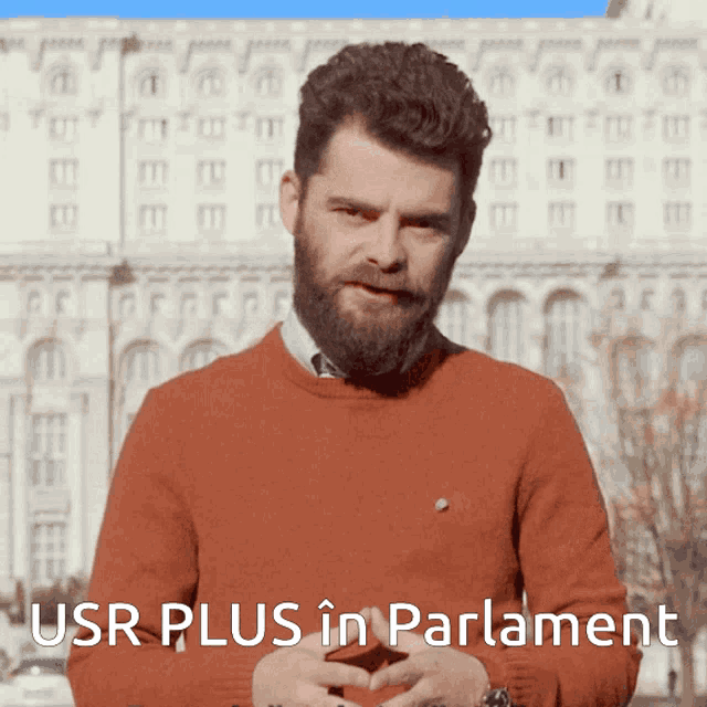 a man with a beard in front of a building with the words usr plus in parliament