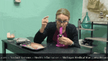 a woman sitting at a table smoking a bong with the website michigan medical marijuana association at the bottom