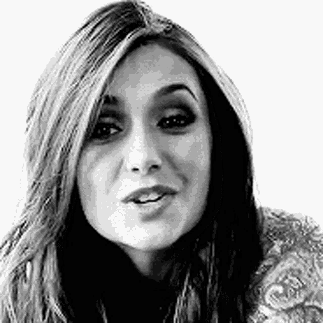 a black and white photo of a woman with long hair and a smile on her face .